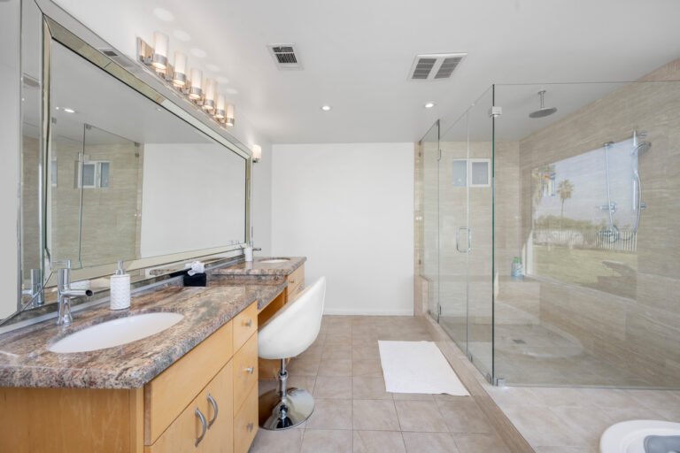 spacious white bathroom with stone countertop lit