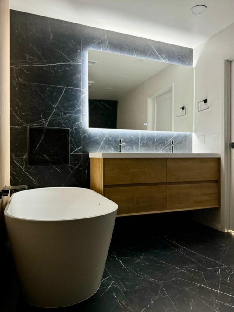 Master bathroom with a standalone tub, LED mirror, big black tile