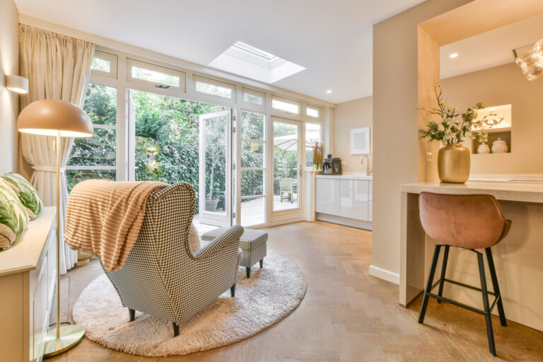 Bright living room with cozy seating, open kitchen, and large glass doors to the garden