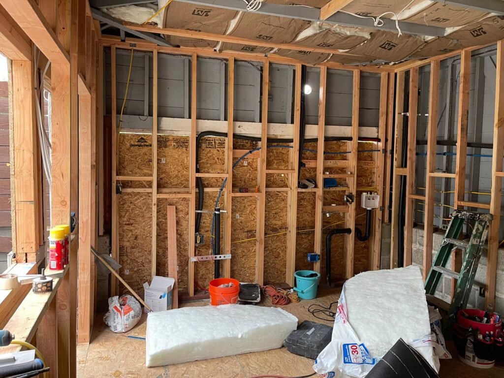 Framing and rough-in plumbing during garage-to-ADU conversion in North Park San Diego, showing insulation and in-progress utilities