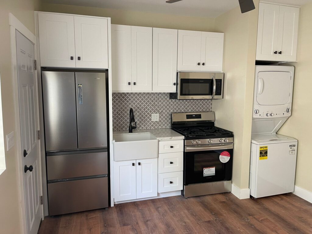 Modern ADU kitchen with white shaker cabinets and tile backsplash from garage conversion in San Diego