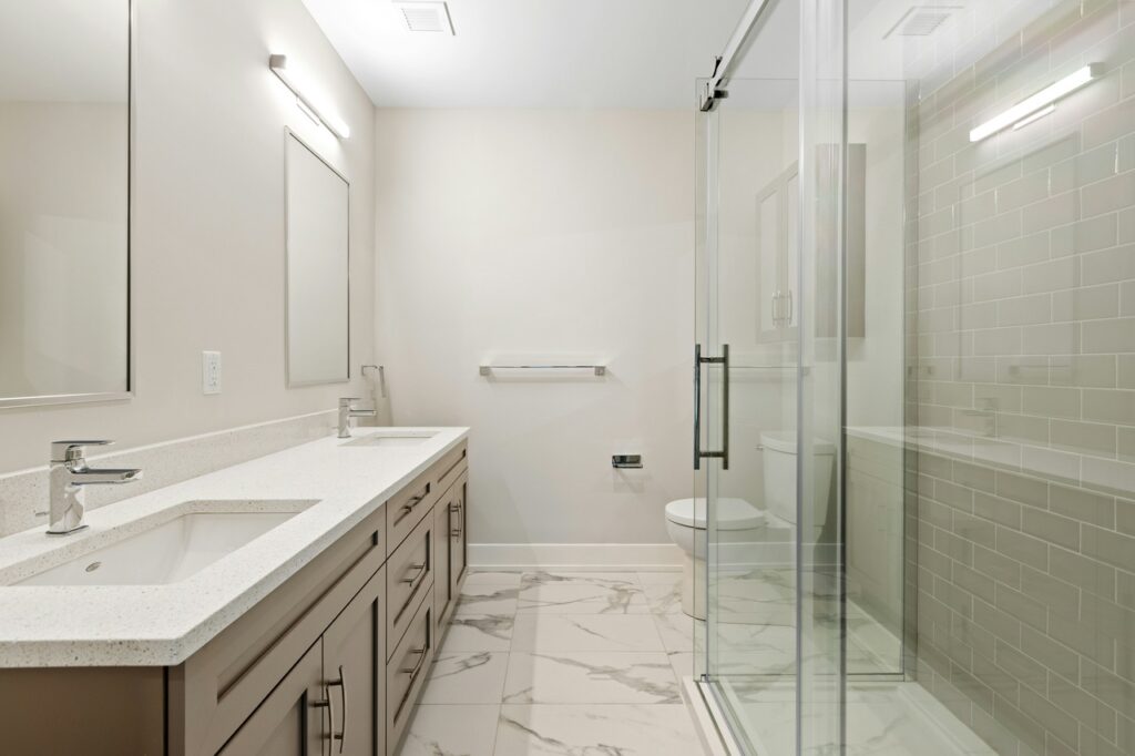 Polished marble-style tile flooring in a modern bathroom with double vanity and glass shower — elegant and durable choice for bathroom remodels