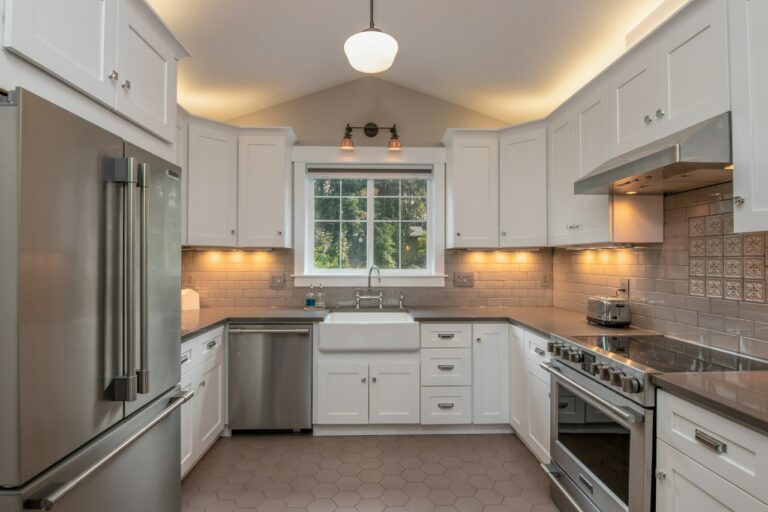 U-shaped kitchen with shaker cabinets, stainless appliances, gray hex tile flooring, and farmhouse sink — stylish and space-efficient remodel