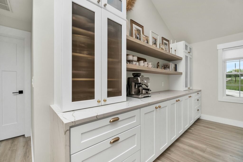 Custom white kitchen cabinetry with marble countertop and built-in coffee station — elegant storage and functional layout