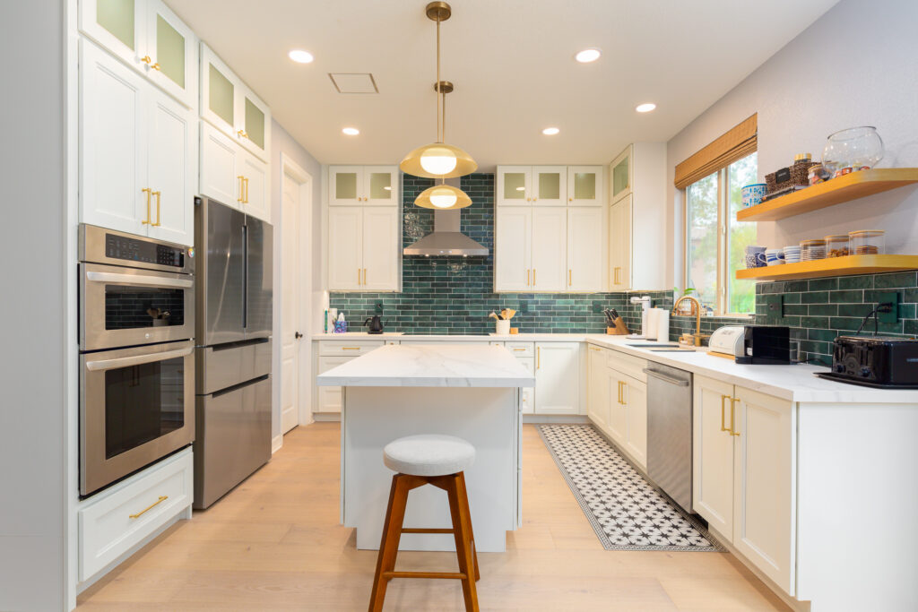 A comprehensive 2026 kitchen remodel in San Diego featuring white shaker cabinets, a textured green tile backsplash, and elegant gold hardware. The space includes warm wood floating shelves and integrated stainless steel appliances, showcasing modern San Diego kitchen design trends. A comprehensive 2026 kitchen remodel in San Diego featuring white shaker cabinets, a textured green tile backsplash, and elegant gold hardware. The space includes warm wood floating shelves and integrated stainless steel appliances, showcasing modern San Diego kitchen design trends.