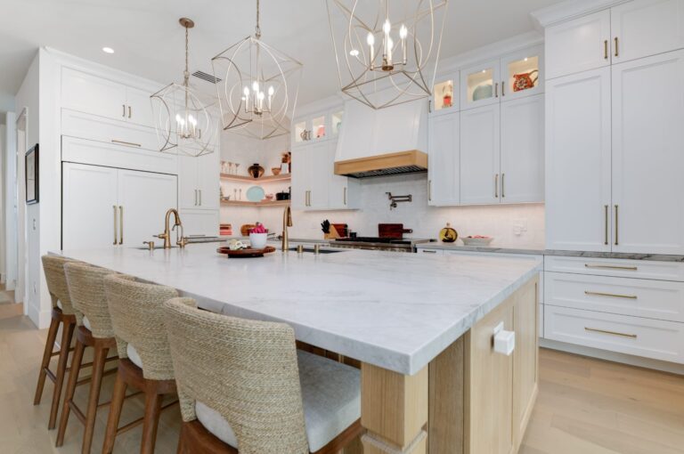 A multifunctional kitchen island in a San Diego home showing integrated seating, warm wood accents, and high-end marble countertops that reflect 2026 design trends