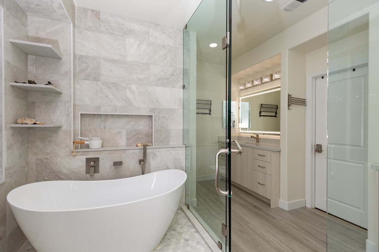 Freestanding soaking tub in a San Diego primary bathroom remodel — sculptural acrylic tub, floor-mounted filler, large window with natural light