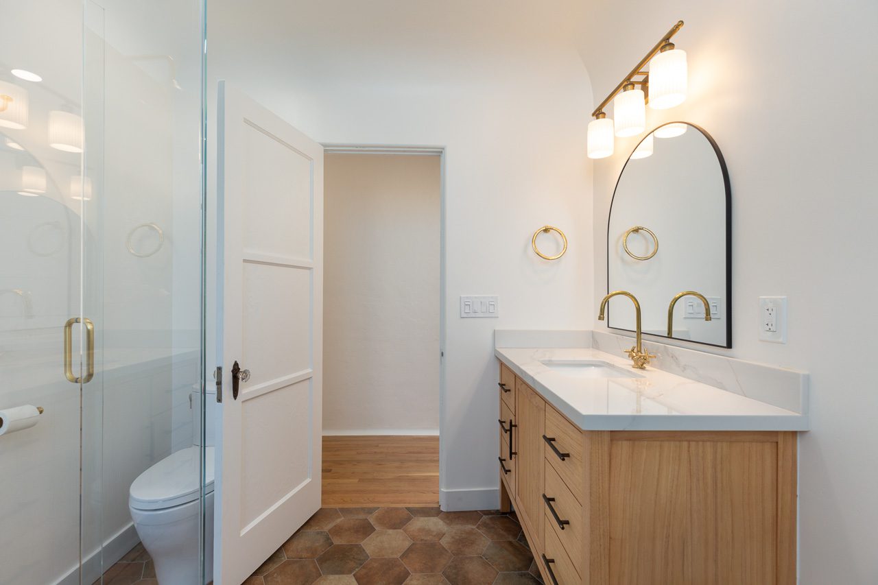 Freestanding soaking tub installation with white oak fluted vanity and arch mirror — historic home remodel Mission Hills San Diego 92103