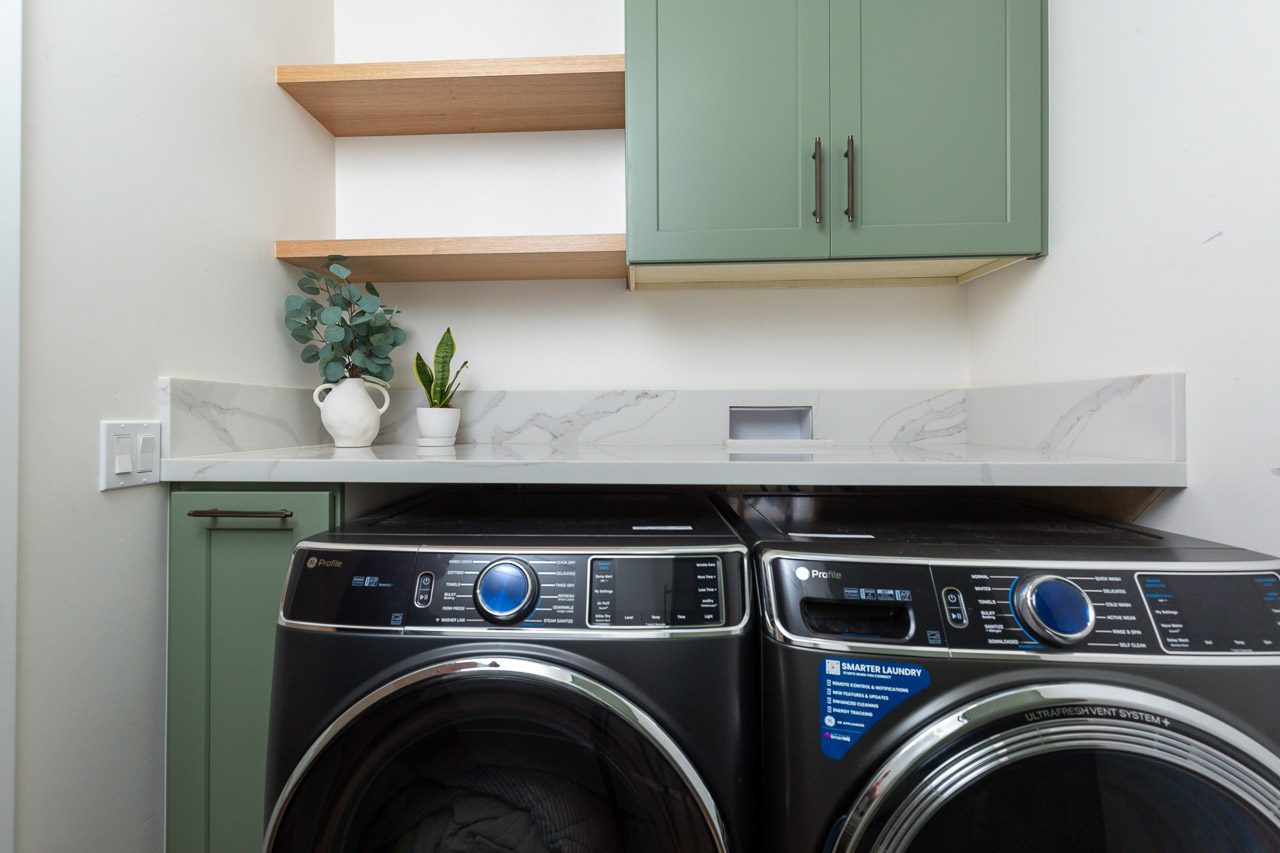 Laundry room detail with GE Profile washer dryer and sage green cabinets, whole home remodel Mission Hills