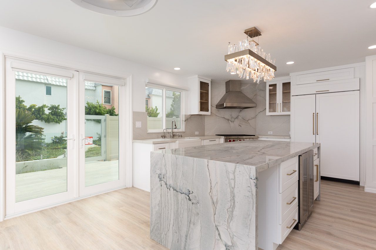 Luxury open-plan kitchen remodel San Diego — slab waterfall island, fluted cabinetry, photogenic front kitchen with adjacent working pantry behind the wall