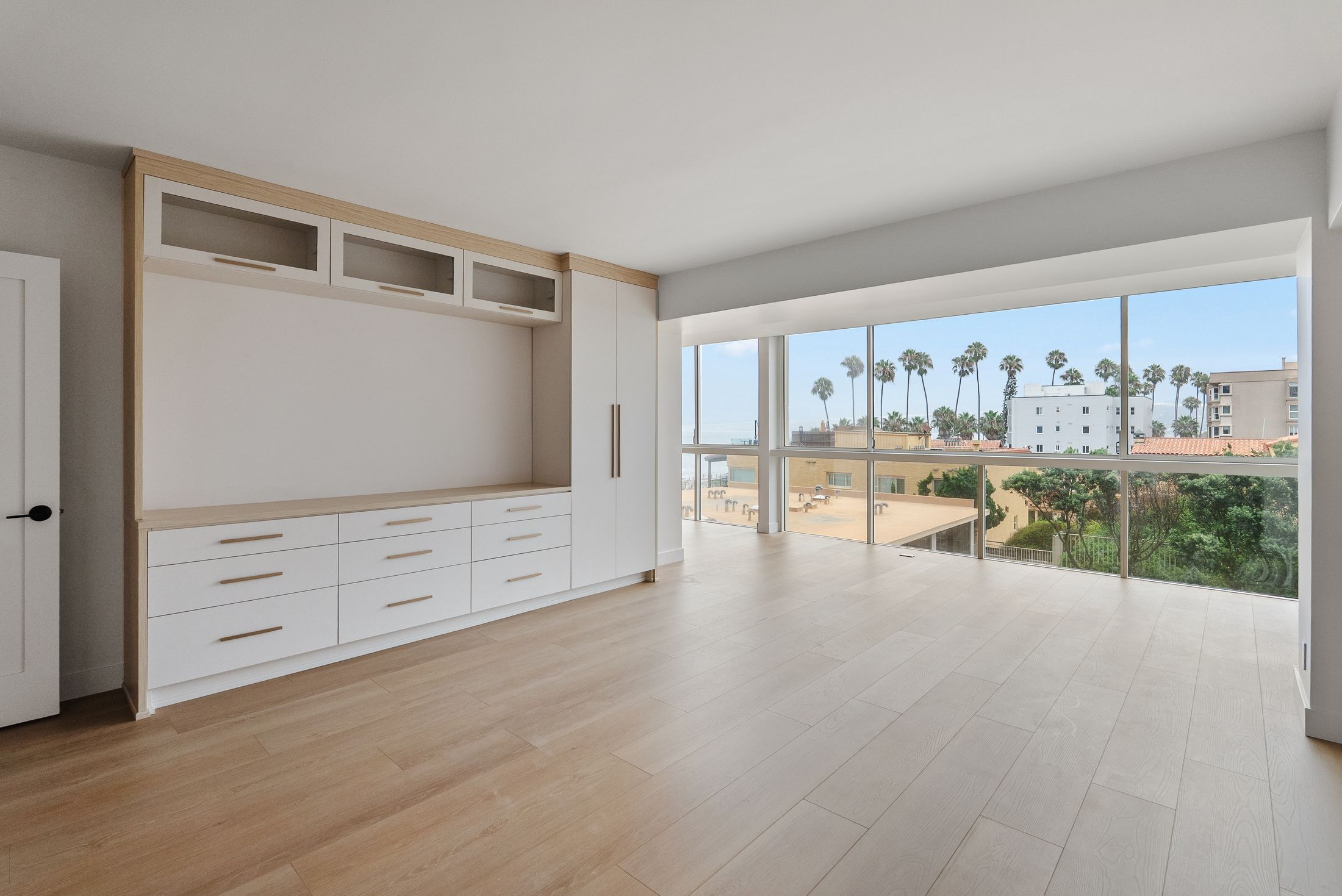 Bedroom built-in wall with matte white drawers, white oak frame and wardrobe facing floor-to-ceiling windows, La Jolla