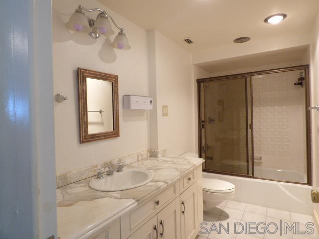 La Jolla guest bathroom before remodel with framed sliding tub doors and cream vanity