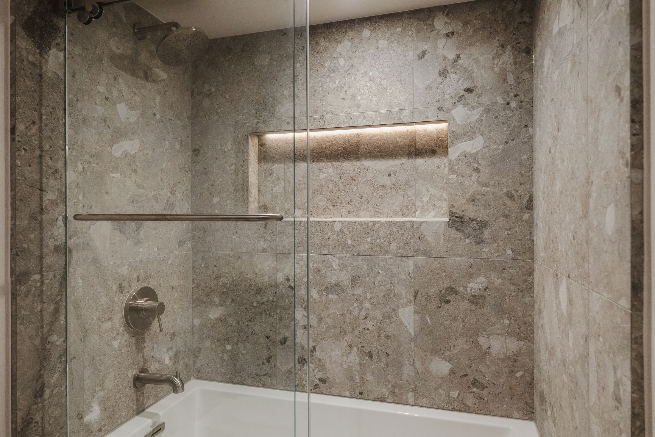 Tub and shower with rain head, brushed nickel valve and lit niche in terrazzo-look tile, La Jolla guest bath