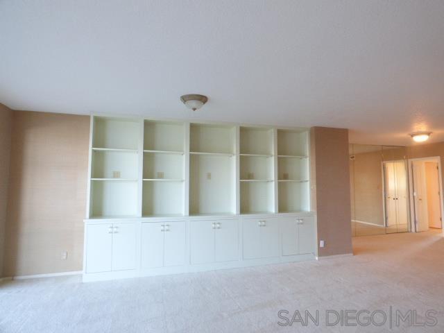 La Jolla living room before remodel with white built-in bookcases and carpet
