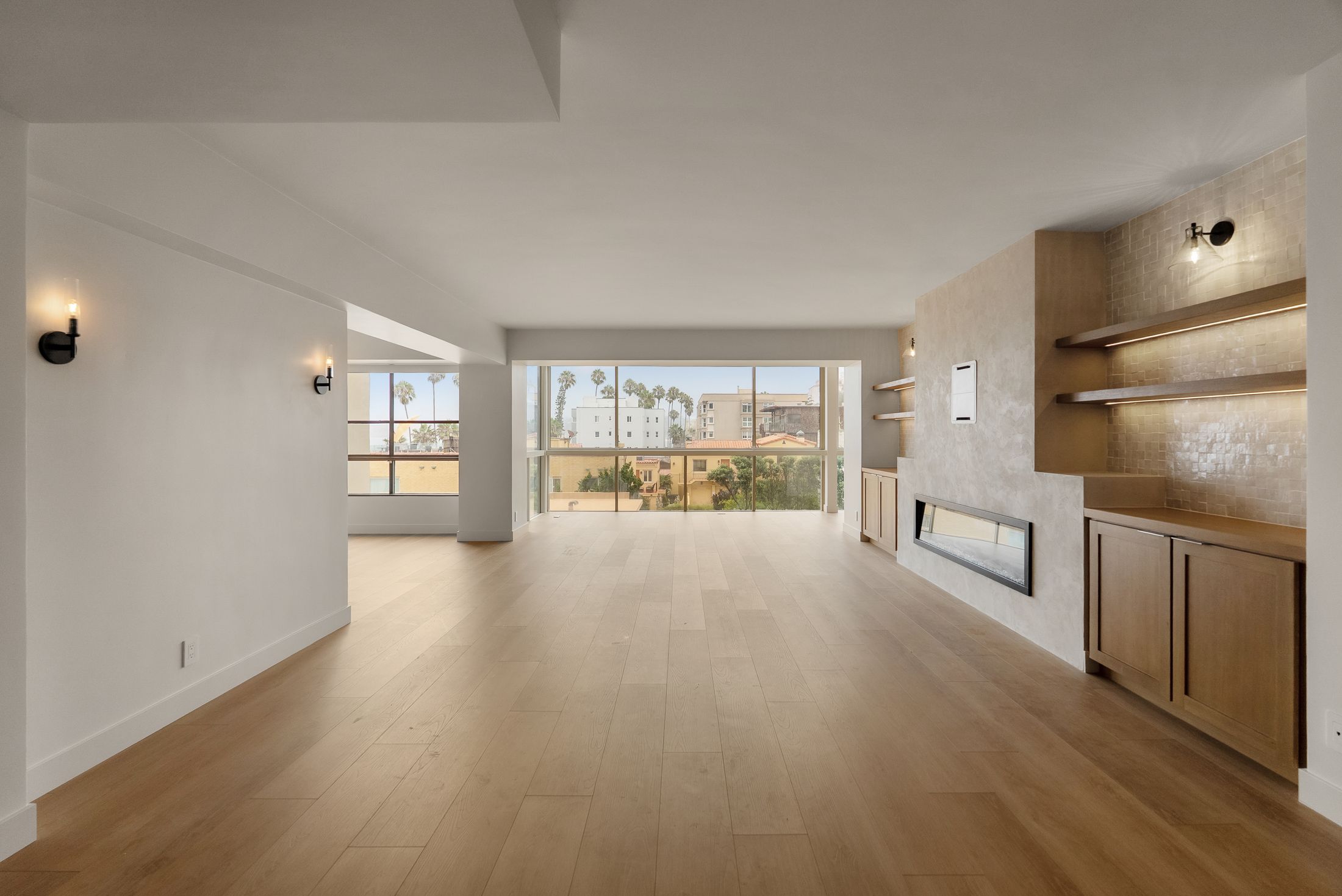 Renovated La Jolla living room with wide-plank flooring, plaster fireplace wall and floor-to-ceiling windows