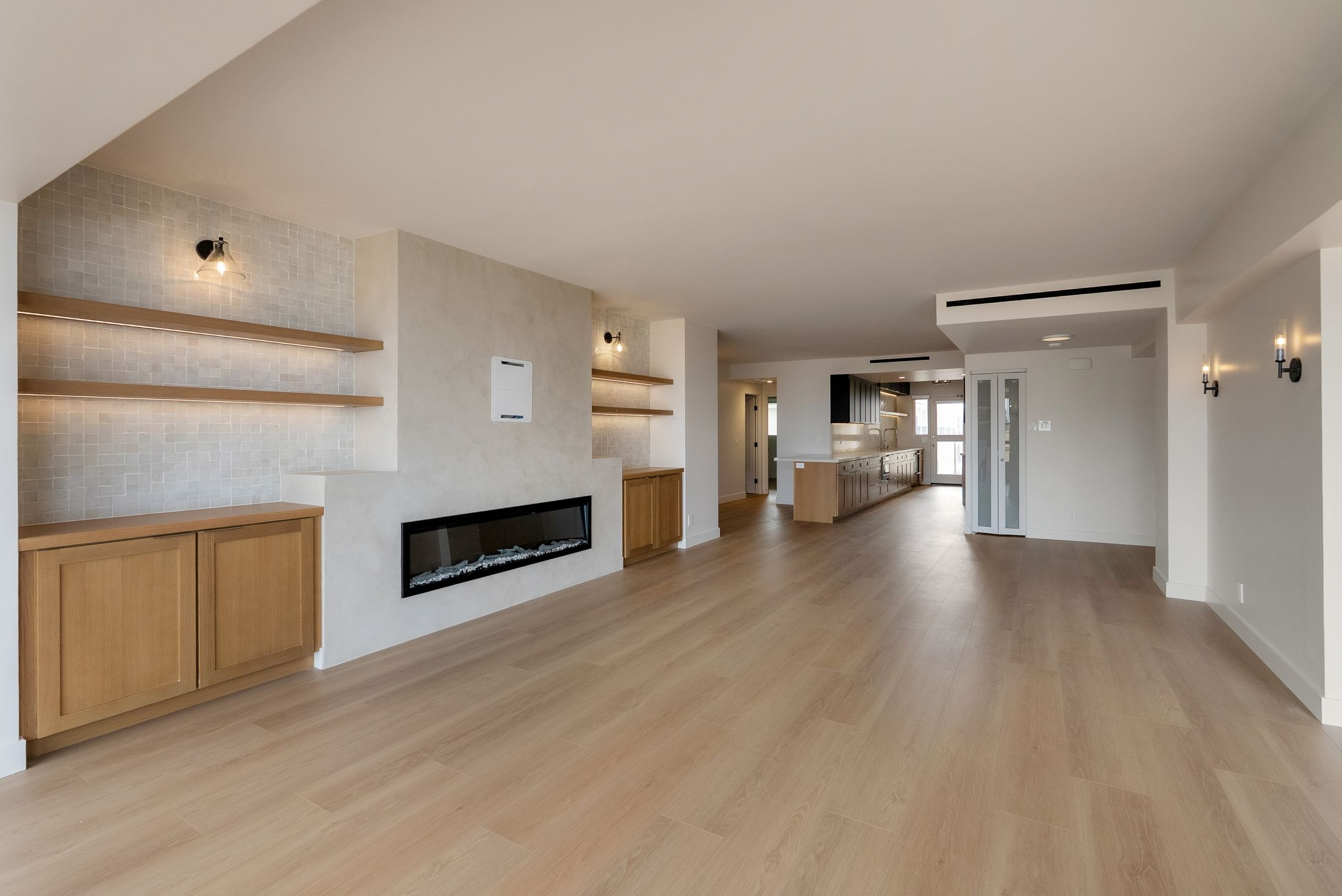 Open-plan La Jolla living room looking toward the remodeled galley kitchen, wide-plank hardwood floors