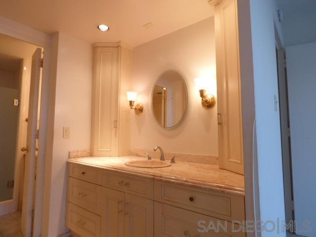 La Jolla primary bathroom before remodel with cream single vanity and oval mirror