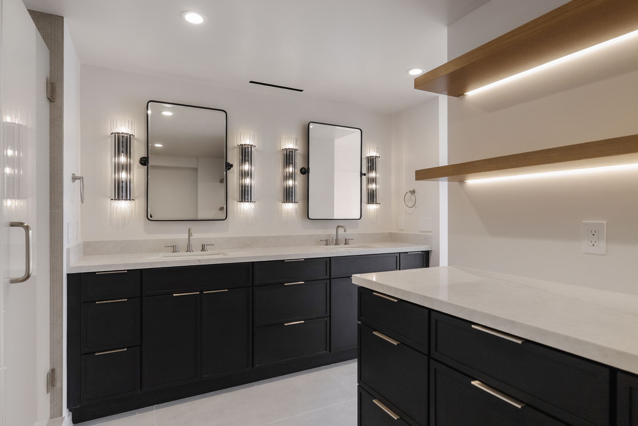 Fluted glass sconces and black-framed mirrors over a double vanity, primary bath remodel in La Jolla 92037