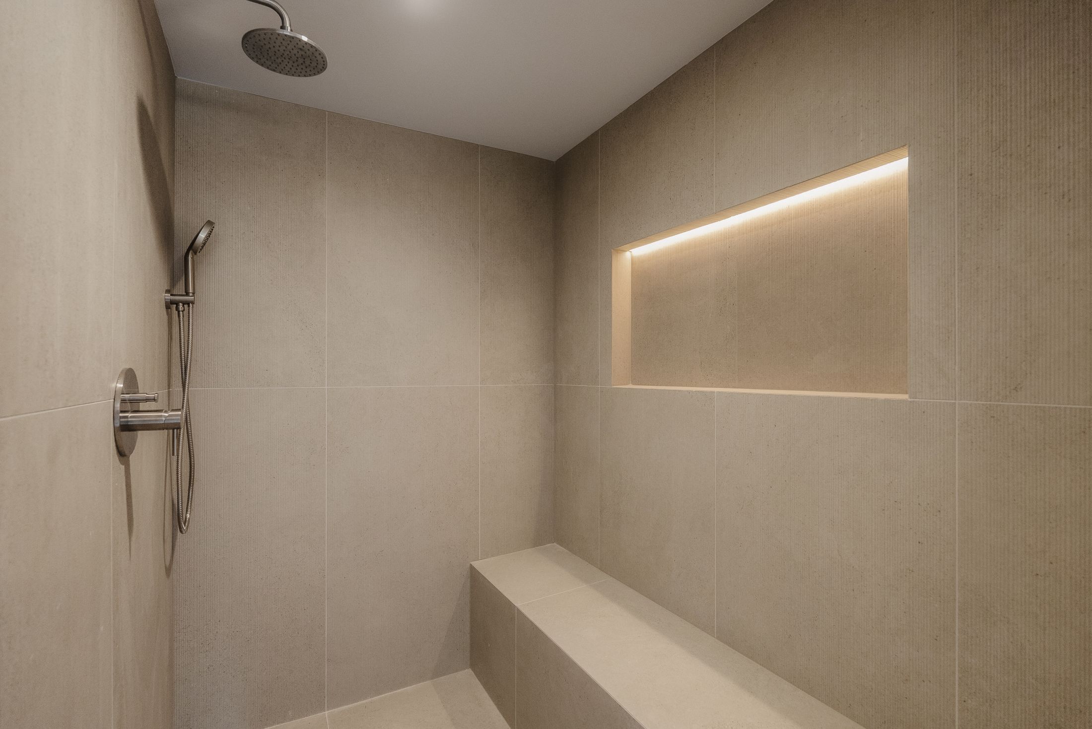 Walk-in shower with built-in bench, LED-lit niche and large-format textured tile, La Jolla primary bath